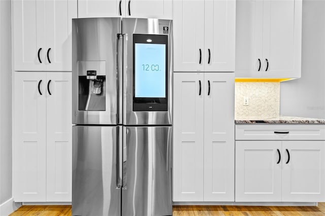 kitchen with backsplash, white cabinetry, light hardwood / wood-style flooring, stainless steel fridge with ice dispenser, and light stone counters