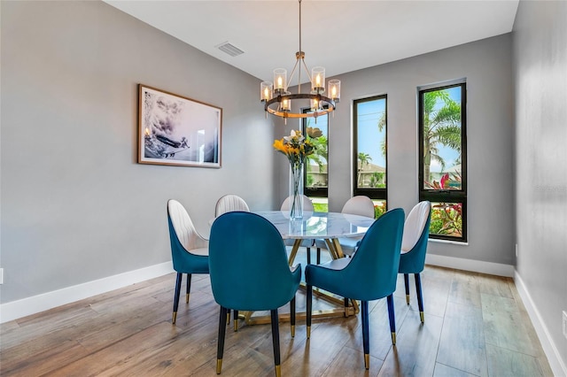 dining space featuring wood-type flooring, a wealth of natural light, and a chandelier