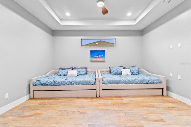 bedroom featuring ceiling fan, light wood-type flooring, and a raised ceiling