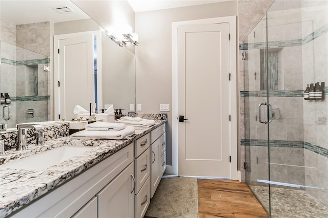 bathroom with a shower with door, hardwood / wood-style flooring, and vanity