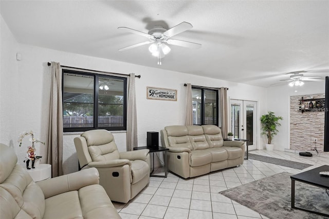 tiled living room with ceiling fan, a textured ceiling, and french doors