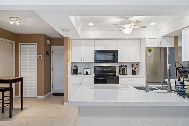 kitchen featuring white cabinetry, a tray ceiling, black appliances, and ornamental molding