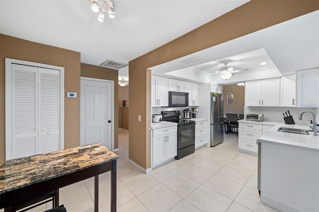 kitchen featuring white cabinets, black appliances, sink, a raised ceiling, and light tile patterned floors