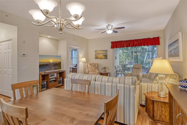 dining room with ceiling fan with notable chandelier and light wood-type flooring