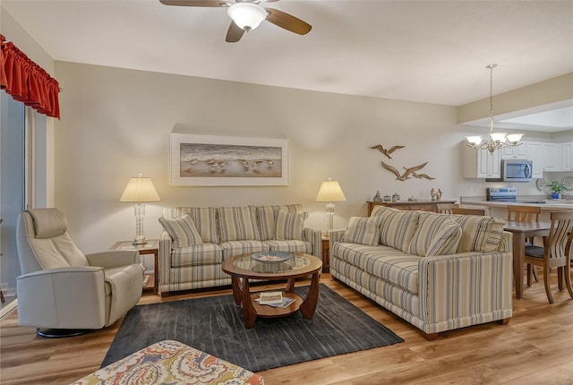 living room with light hardwood / wood-style floors and ceiling fan with notable chandelier