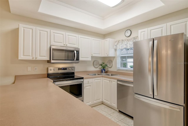 kitchen with a raised ceiling, sink, appliances with stainless steel finishes, white cabinets, and light tile patterned floors