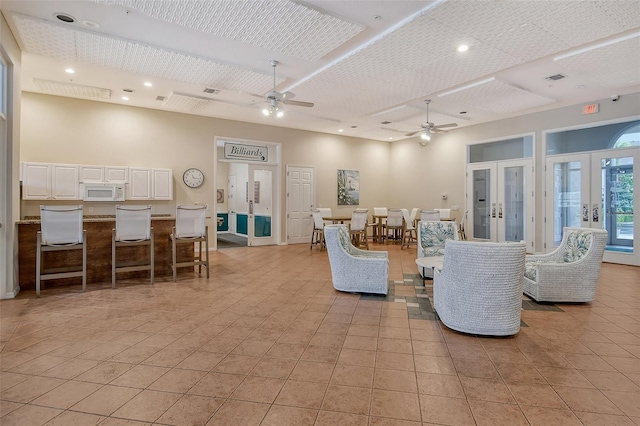 living room featuring a towering ceiling, ceiling fan, light tile patterned floors, and french doors