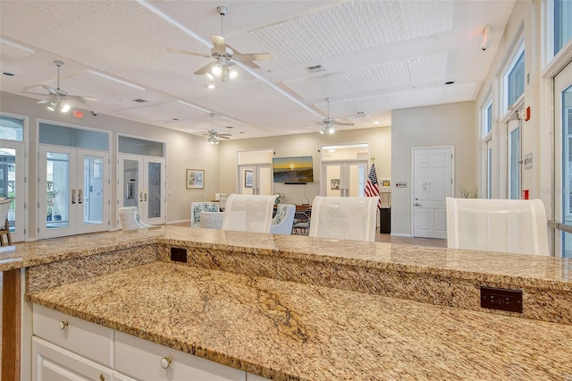 kitchen featuring french doors, white cabinetry, and light stone countertops