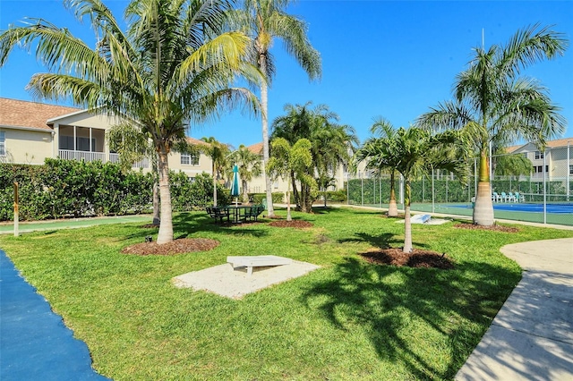 view of property's community with tennis court and a yard