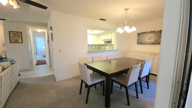 carpeted dining area featuring ceiling fan with notable chandelier