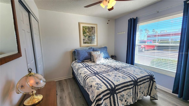 bedroom with ceiling fan, wood-type flooring, a closet, and a textured ceiling