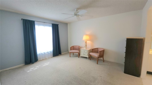 sitting room featuring light carpet, ceiling fan, and a textured ceiling