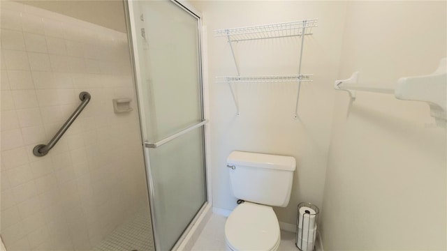 bathroom featuring a shower with door and toilet