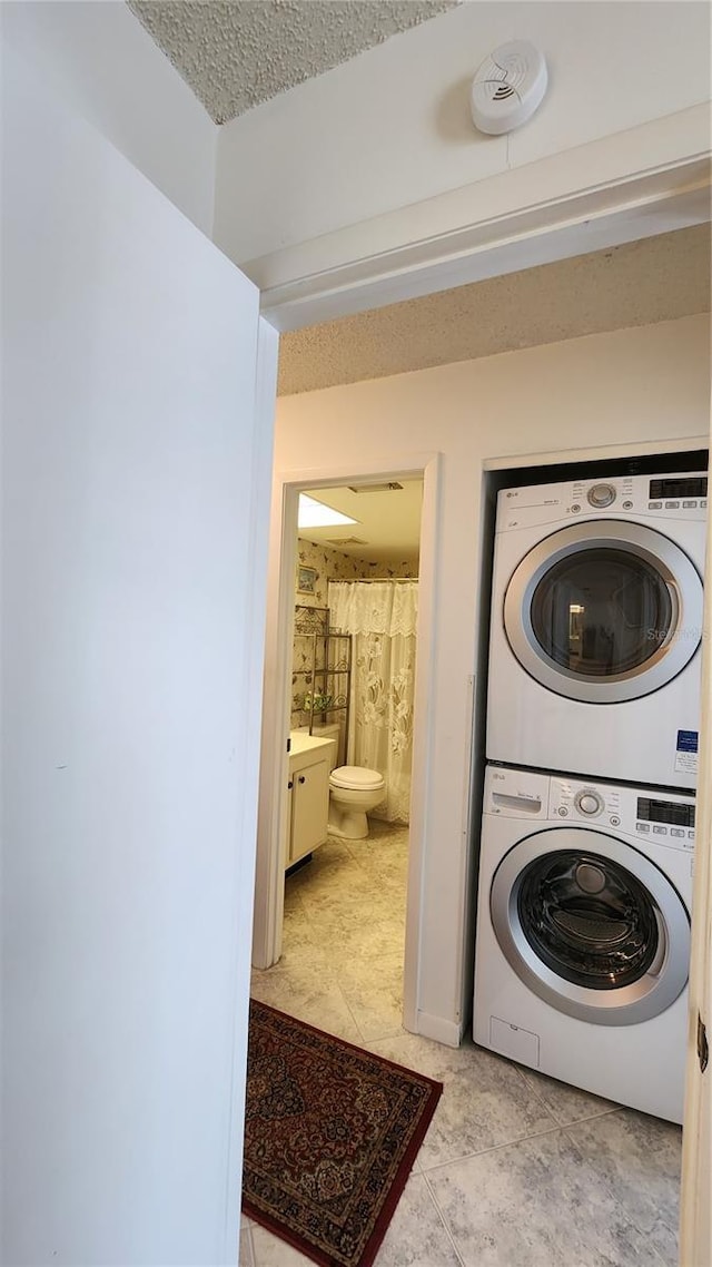 laundry room with stacked washer and dryer and a textured ceiling