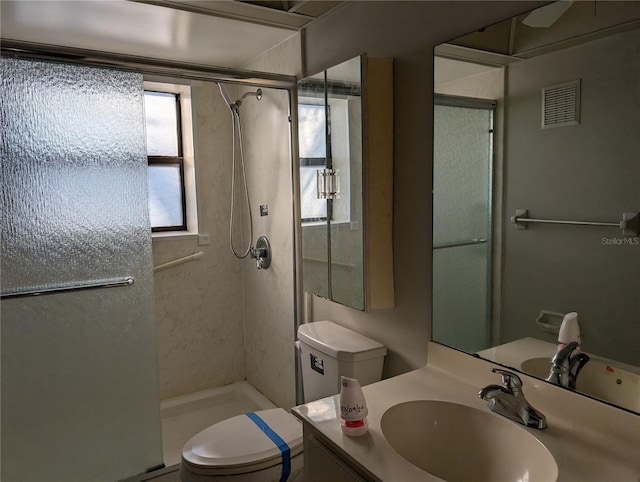 bathroom with a shower with shower door, toilet, and vanity