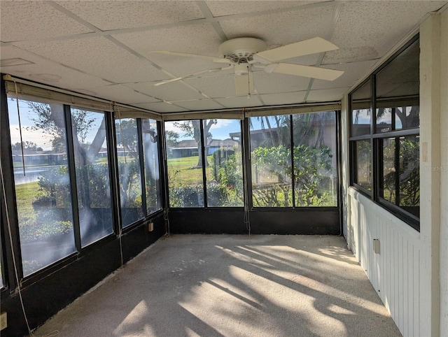 unfurnished sunroom featuring ceiling fan, a drop ceiling, and a water view