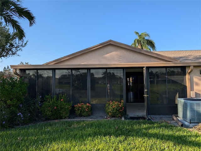 rear view of property featuring a lawn, a sunroom, and central AC