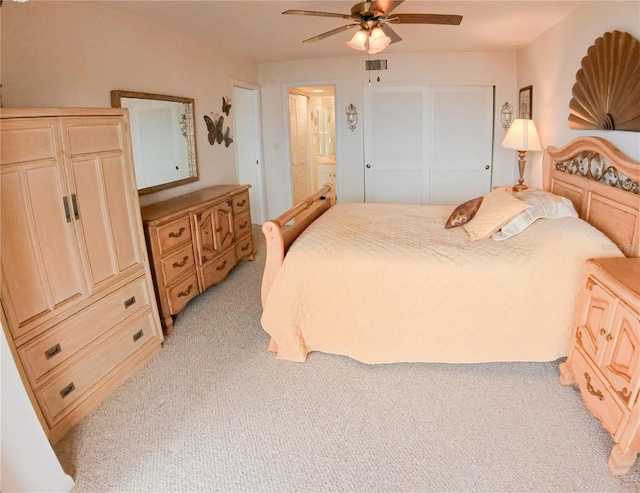 bedroom featuring connected bathroom, light carpet, and ceiling fan