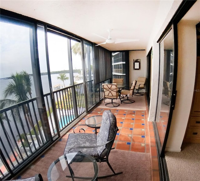 sunroom / solarium with ceiling fan and a water view