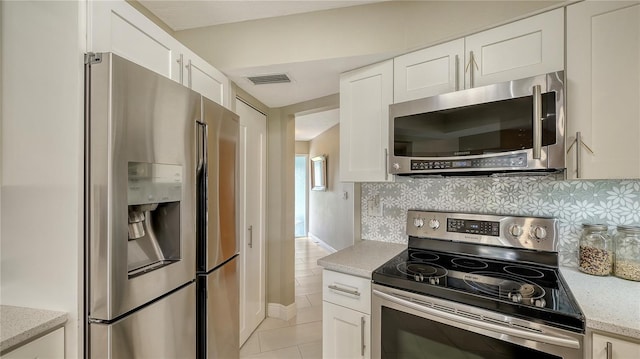 kitchen with backsplash, appliances with stainless steel finishes, light tile patterned floors, and white cabinets