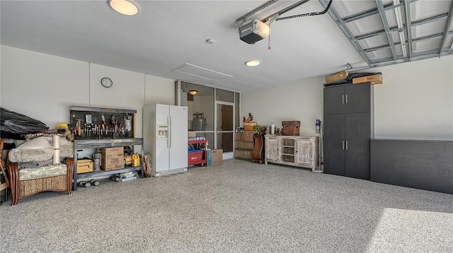 garage with a garage door opener and white fridge with ice dispenser