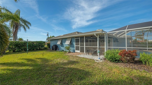 rear view of property with ceiling fan, a lanai, and a lawn