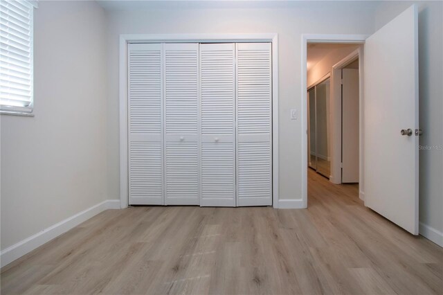 unfurnished bedroom with light hardwood / wood-style flooring and a closet