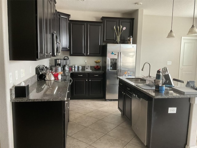 kitchen featuring stainless steel appliances, an island with sink, sink, and light tile patterned floors