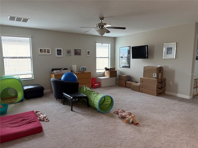 rec room featuring ceiling fan, light colored carpet, and a textured ceiling