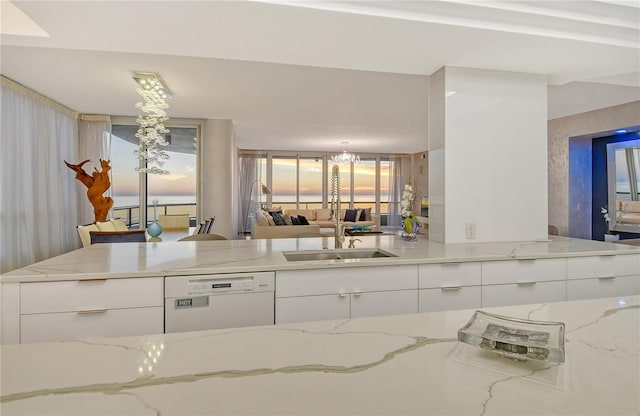 kitchen with white cabinets, light stone countertops, sink, and dishwasher