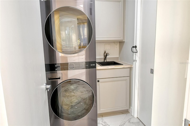 washroom featuring stacked washer and dryer, sink, and cabinets