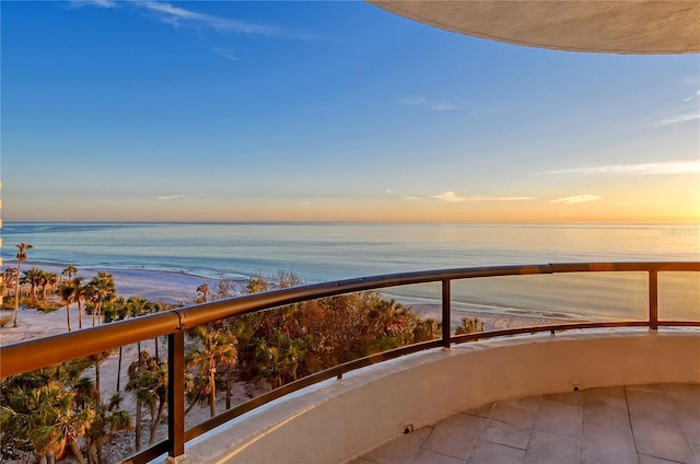 balcony at dusk featuring a water view