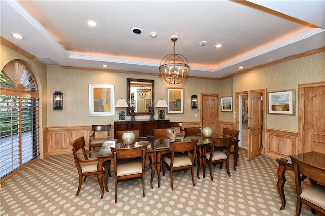 carpeted dining space featuring ornamental molding, a tray ceiling, and a notable chandelier