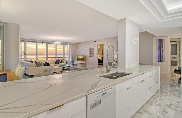 kitchen featuring white cabinetry, dishwasher, sink, a chandelier, and light stone counters