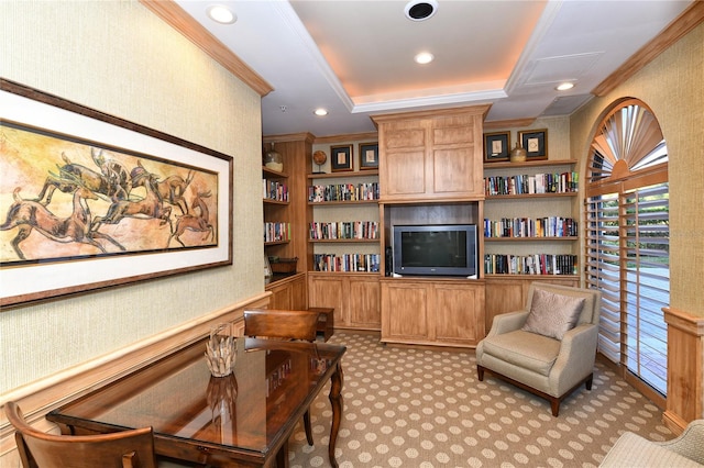 carpeted living room with a tray ceiling, built in shelves, and ornamental molding