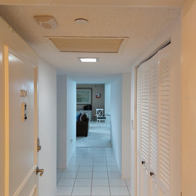 hall featuring light tile patterned floors and a textured ceiling