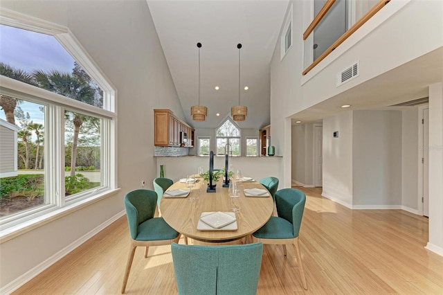 dining area featuring light hardwood / wood-style floors and high vaulted ceiling