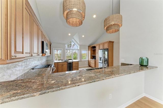 kitchen with kitchen peninsula, stone countertops, wine cooler, decorative light fixtures, and lofted ceiling