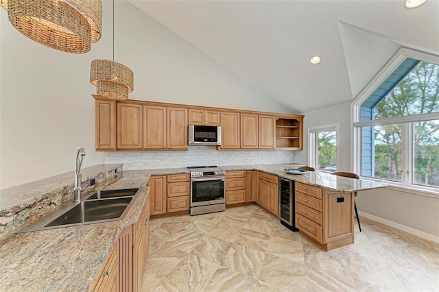 kitchen with beverage cooler, stainless steel appliances, sink, hanging light fixtures, and kitchen peninsula