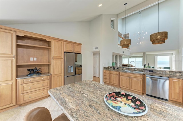 kitchen with light stone countertops, hanging light fixtures, sink, high vaulted ceiling, and stainless steel appliances