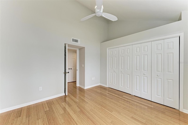 unfurnished bedroom featuring a closet, ceiling fan, high vaulted ceiling, and light wood-type flooring