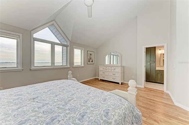 bedroom with ceiling fan, light wood-type flooring, high vaulted ceiling, and ensuite bathroom