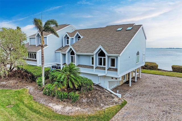 view of front of property featuring a carport, a shingled roof, decorative driveway, and a water view