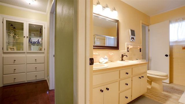 bathroom featuring toilet, tasteful backsplash, crown molding, wood-type flooring, and vanity