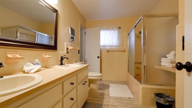 full bathroom featuring vanity, decorative backsplash, bath / shower combo with glass door, and toilet