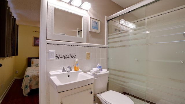 bathroom with vanity, toilet, a shower with door, and a textured ceiling