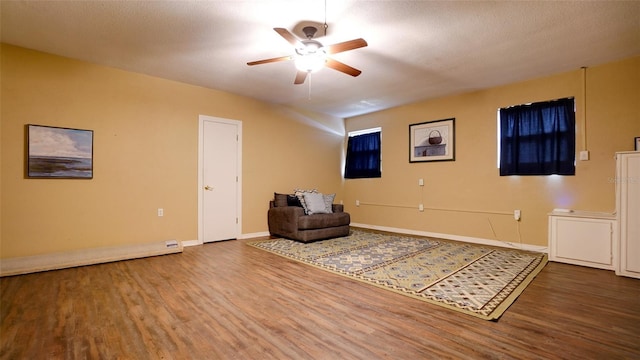 living area with a textured ceiling, wood-type flooring, and ceiling fan