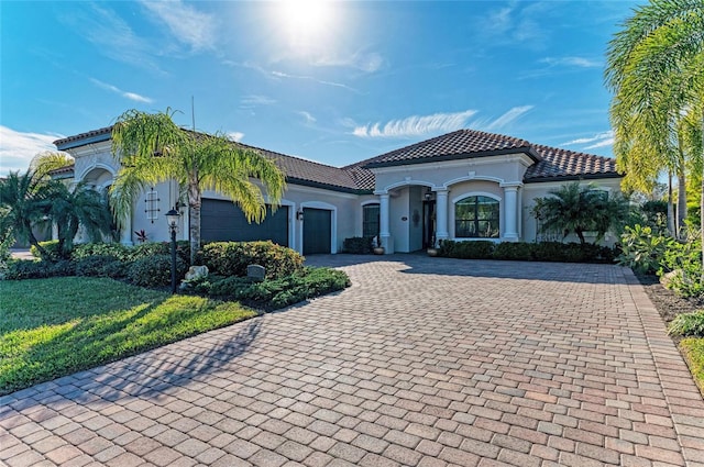 mediterranean / spanish-style house featuring a garage and a front lawn