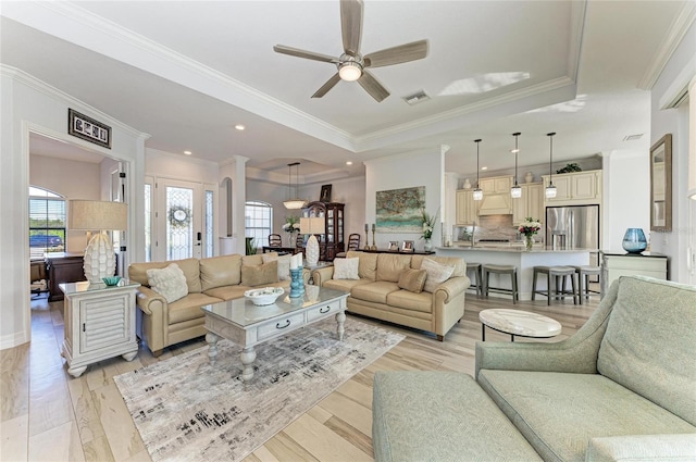 living room with a raised ceiling, ornamental molding, ceiling fan, and light hardwood / wood-style flooring