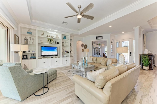 living room with ceiling fan, ornamental molding, a raised ceiling, and light hardwood / wood-style floors